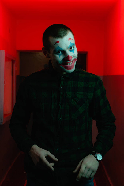 Close-up portrait of a joker man. Stock photo makeup joker in a horror room. - Photo, Image