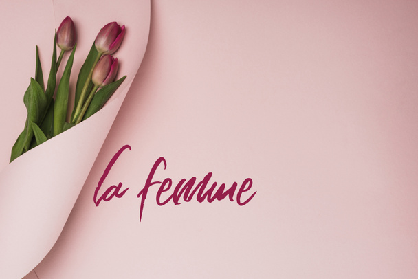 top view lila tulipán csomagolva papír rózsaszín háttér, la femme illusztráció - Fotó, kép