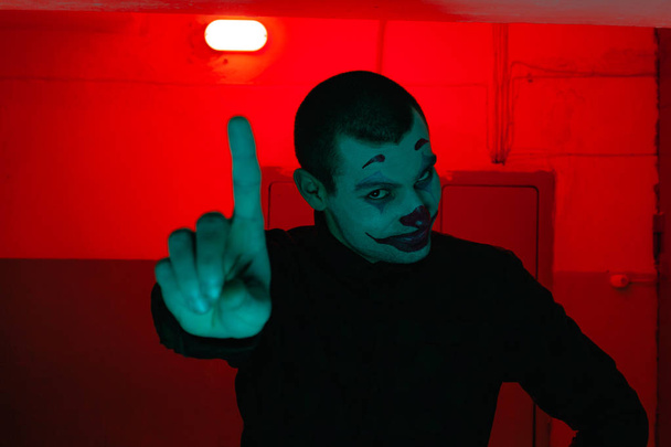Close-up portrait of a joker man. Stock photo makeup joker in a horror room. - Photo, Image