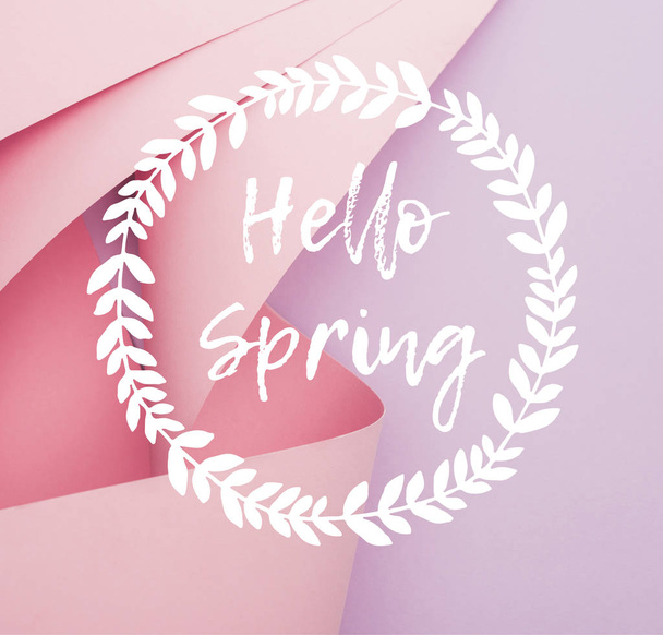 bovenaanzicht van roze papieren wervelingen op violette achtergrond, hallo voorjaar illustratie - Foto, afbeelding