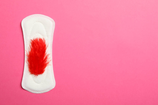 Sanitary pad with red feather on pink background, top view - Photo, Image