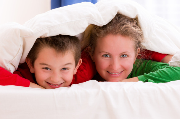 Madre e hijo bajo manta sonriendo alegremente
 - Foto, imagen