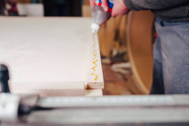  Joiner applies glue for gluing wooden planks - 写真・画像
