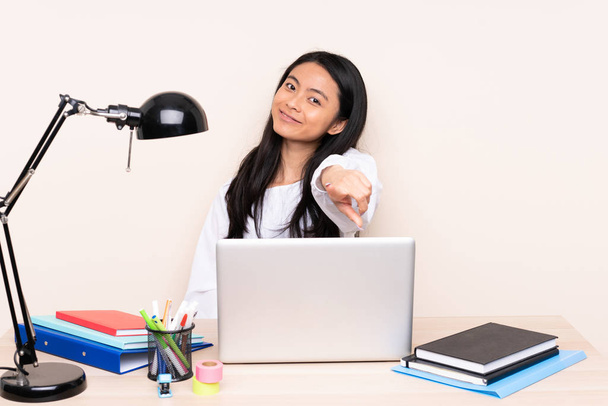Studente ragazza asiatica in un posto di lavoro con un computer portatile isolato su sfondo beige punti dito a voi con un'espressione fiduciosa
 - Foto, immagini