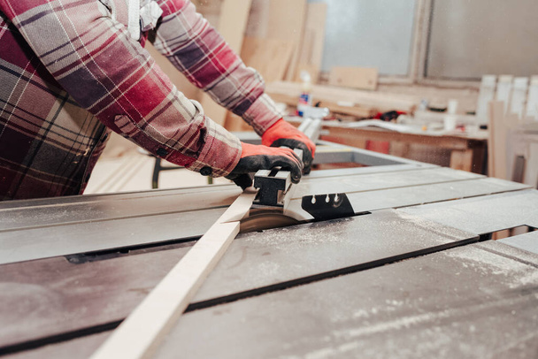 Carpenter cuts plywood on a circular saw - Φωτογραφία, εικόνα