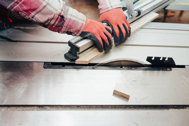Carpenter cuts plywood on a circular saw - 写真・画像
