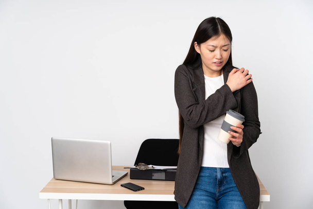 Mujer asiática de negocios en su lugar de trabajo aislada sobre fondo blanco sufriendo de dolor en el hombro por haber hecho un esfuerzo
 - Foto, Imagen