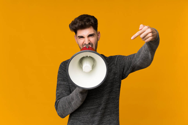 Mladý muž na izolovaném pozadí křičí přes megafon - Fotografie, Obrázek