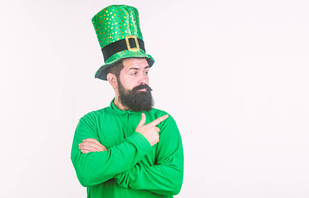 Happy saint patricks day. Bearded man celebrating saint patricks day. Hipster in green leprechaun hat and costume. Irish man with beard pointing his finger. Look over there, copy space - Photo, image