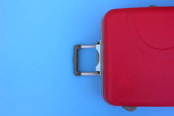 Hot pink plastic suitcase lies against a blue sky background, carry-on luggage for traveling - Фото, изображение