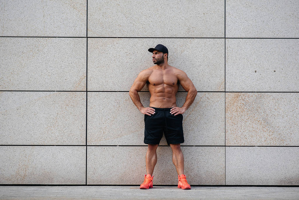 sexy sportsman stands topless near the wall. Fitness, bodybuilding - Zdjęcie, obraz