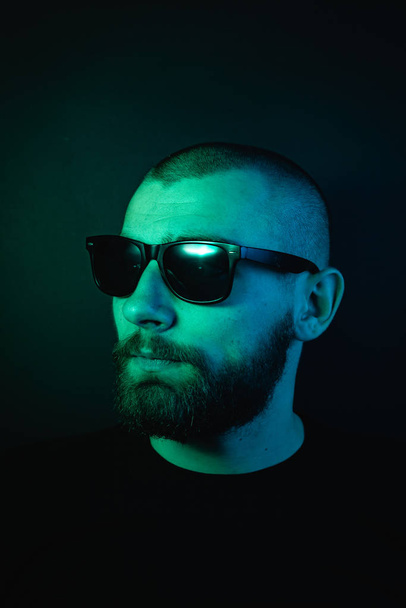 Portrait d'un hipster avec lumière de couleur. Portrait visage hippie en studio
. - Photo, image