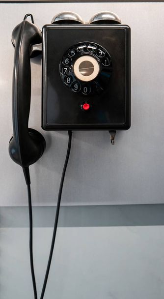 Wall mounted black vintage classic disc dial phone with cord isolated close up shot 2020 - Foto, Bild