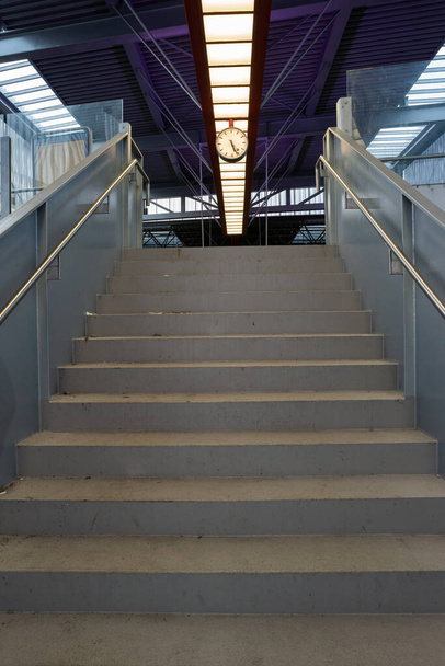 alacsony szögű kilátás az ipari lépcsőn vezető felső szerelt analóg óra egy vasútállomás 2020 - Fotó, kép