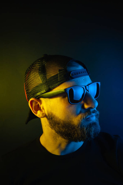 Portrait of a hipster guy with color light. Hipster face portrait in studio. - 写真・画像