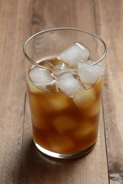 Glass of coffee with ice on wooden table - Foto, Imagen
