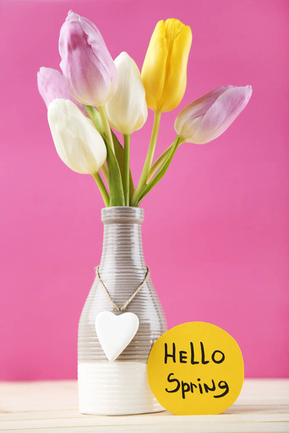 Tulip flowers in vase with text Hello Spring on pink background - Valokuva, kuva
