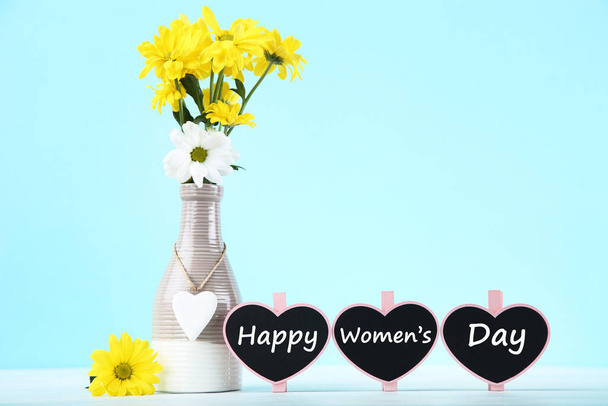 Text Happy Womens Day with chrysanthemum flowers in vase on blue background - Foto, imagen