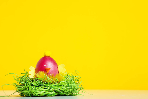 Cute easter egg with green nest on yellow background - Fotografie, Obrázek