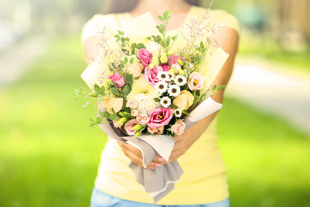 Female hands holding beautiful flower bouquet in the park - Фото, зображення