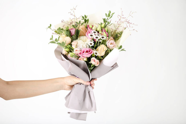 Female hand holding beautiful flower bouquet on white background - Фото, изображение