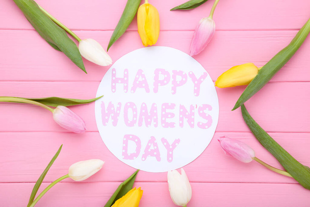 Text Happy Womens Day with tulip flowers on pink wooden table - Foto, imagen