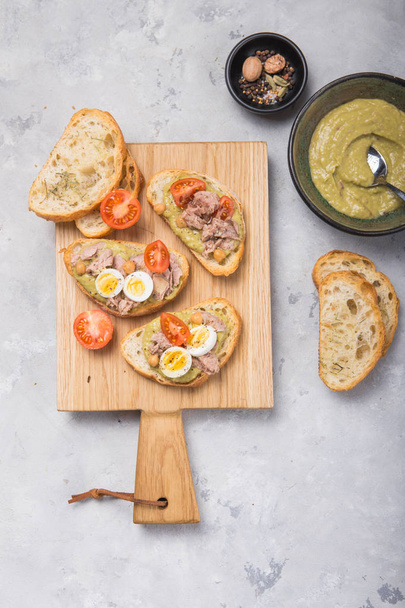 Bruschetta z tuńczykiem, pomidorem, jajkiem i awokado rozłożone. - Zdjęcie, obraz