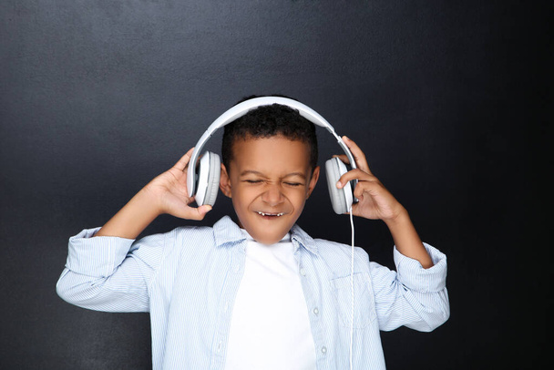 Young African American boy in headphones on black background - Photo, Image