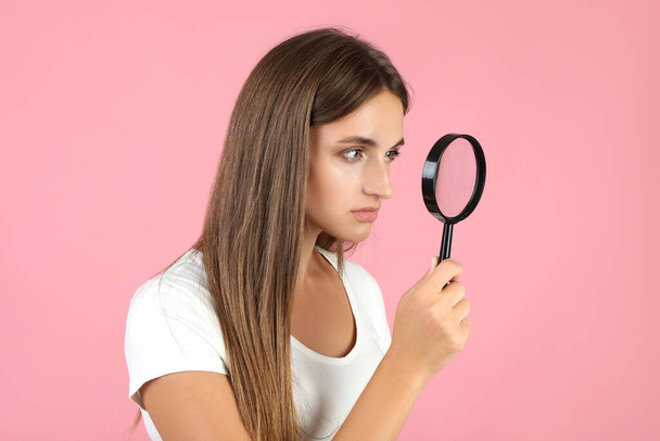 Young woman with magnifying glass on pink background - Fotografie, Obrázek