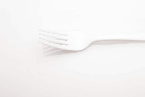 Kunststof vork op gekleurde achtergrond; vork voor casual voedsel, bedekt met wit tot prikken en maken casual voedsel, ideaal voor familie maaltijden, feesten, catering. - Foto, afbeelding