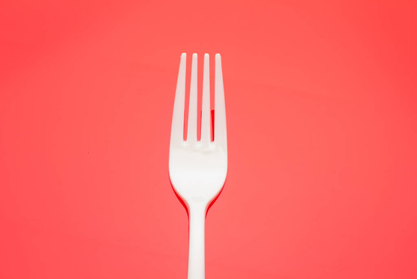 Plastic fork on colored background; fork for casual food, covered in white to prick and make casual food, ideal for family meals, parties, catering. - Photo, Image