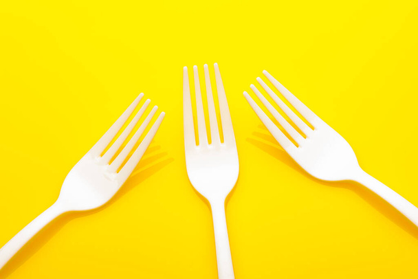 Plastic fork on colored background; fork for casual food, covered in white to prick and make casual food, ideal for family meals, parties, catering. - Photo, Image
