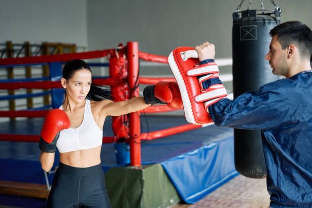 Female boxer kick boxing mitts held by personal trainer at fitness gym. Healthy lifestyle concept               - Fotografie, Obrázek