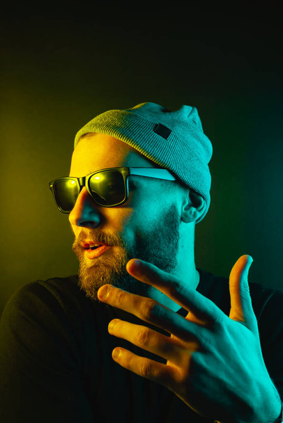 Portrait of a hipster guy with color light. Hipster face portrait in studio. - Фото, зображення