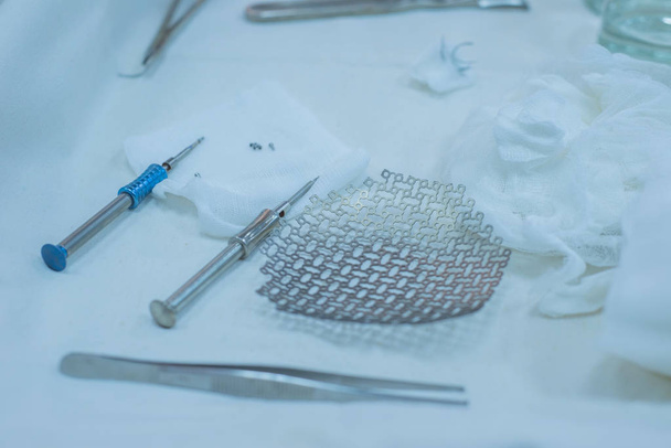 Schedelklem met pinnen en antiseptische oplossing voor hoofdfixatie in neurochirurgische operatiekamer neurochirurgische instrumenten, waaronder een titanium plaat voor implantatie in de schedel, zijn op de steriele operatietafel van een verpleegkundige in de operatine - Foto, afbeelding