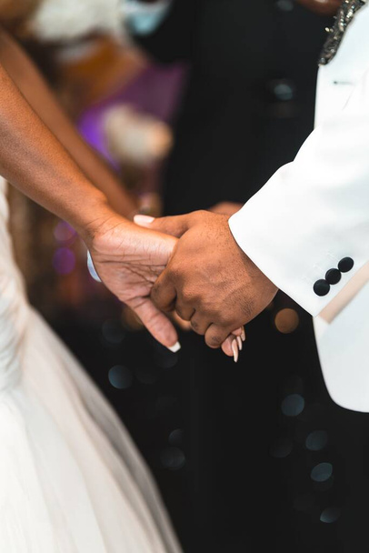 A closeup shot of a bride and a groom facing each other and holding hands - Foto, imagen