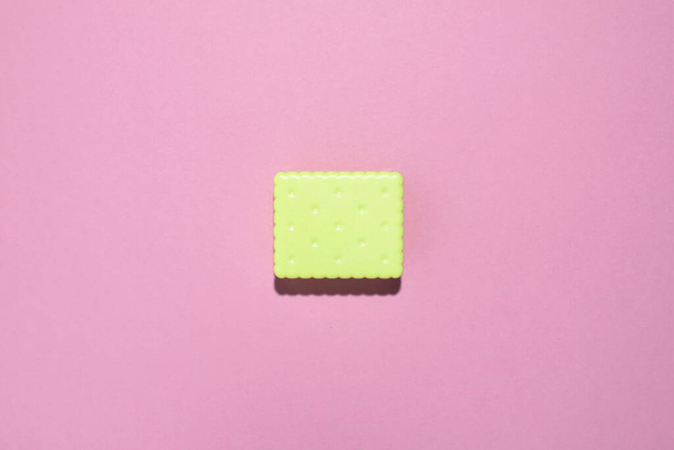 Minimal creative flat lay with decorative green cracker at pink paper background. Color contrast concept. - Fotó, kép