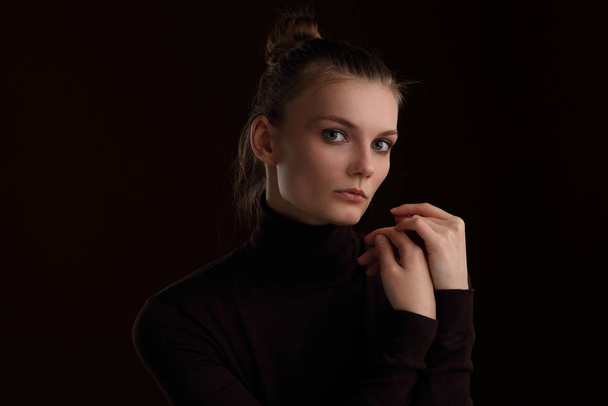 Studio portrait of a beautiful slender girl in a maroon turtleneck on a brown background - Foto, afbeelding