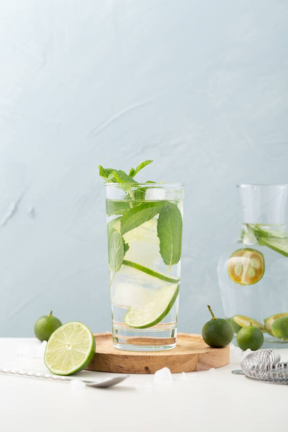 A vertical shot of a glass of lemonade filled with lime and mint on wood with a blue background - Foto, afbeelding
