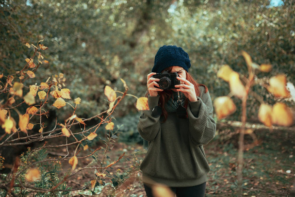 Молодая женщина фотографирует в лесу со старой аналоговой камерой - Фото, изображение