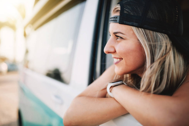 Joven mujer sonriente mira por la ventana de la furgoneta
 - Foto, imagen