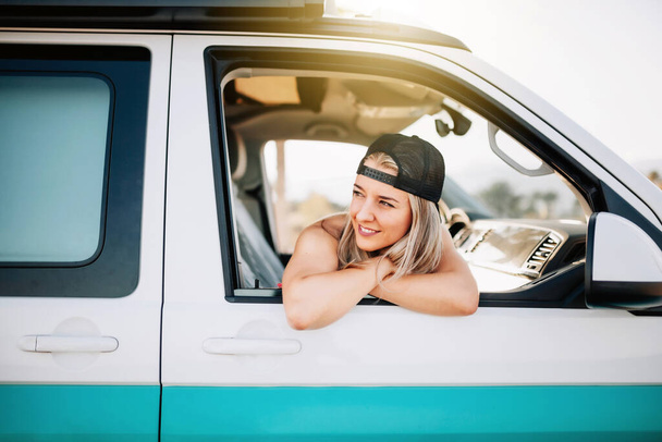 Fiatal, mosolygós nő néz ki a furgon ablakán. - Fotó, kép