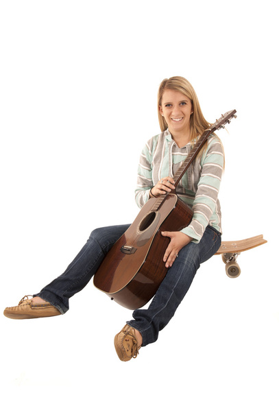smiling woman sitting on skate board with guitar - Photo, image