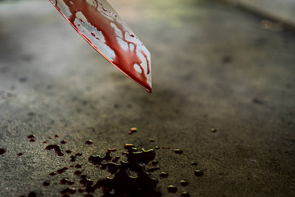 Primo piano del coltello con macchie di sangue e gocciolamento sul pavimento
. - Foto, immagini