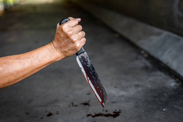 Primer plano del cuchillo con manchas de sangre y goteo en el suelo
. - Foto, imagen