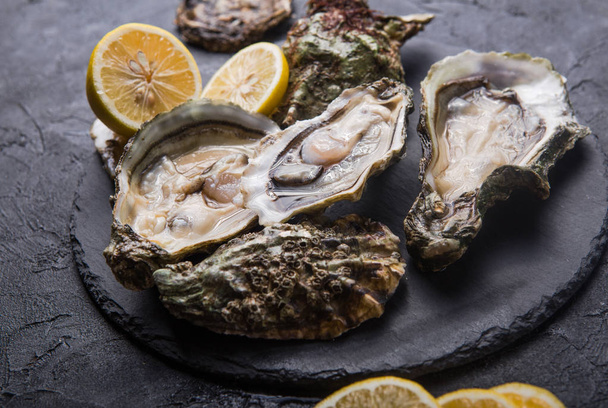 Fresh open Oysters. Healthy sea food. Dinner in restaurant. Gourmet food. Dark background. Top view Healthy sea food. - Photo, Image