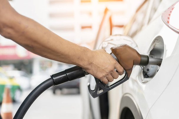 staff hand  filling gasoline fuel in white car holding nozzle with blur station background - Foto, Bild