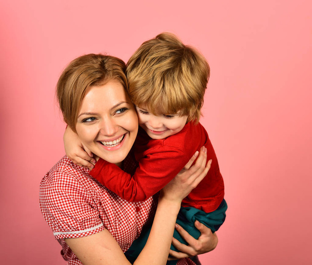 Mother hugs son on pink background. Woman and little boy - Foto, Imagen