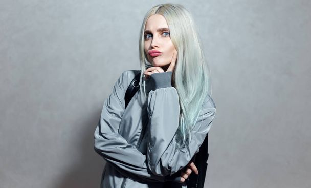 Portrait of cheerful young blonde girl with blue eyes on grey background. - Valokuva, kuva
