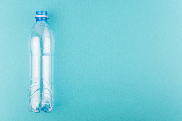 Empty plastic bottle on blue background with copy space for text. Concept of Recycling plastic and ecology. Flat lay, top view - Foto, Bild